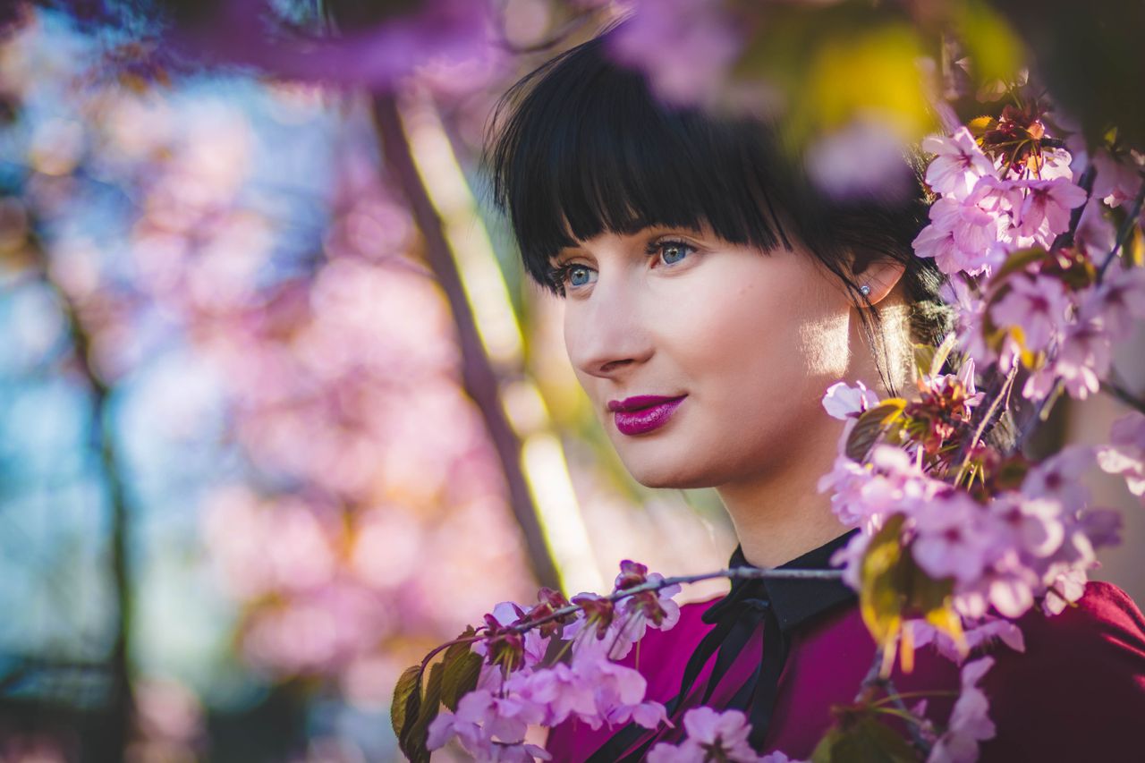 Services Close-up portrait of a woman surrounded by cherry blossoms showcasing spring beauty and fashion.