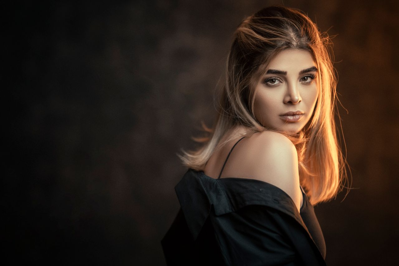 Home Glamorous woman posing in a studio with a dark background and elegant lighting.