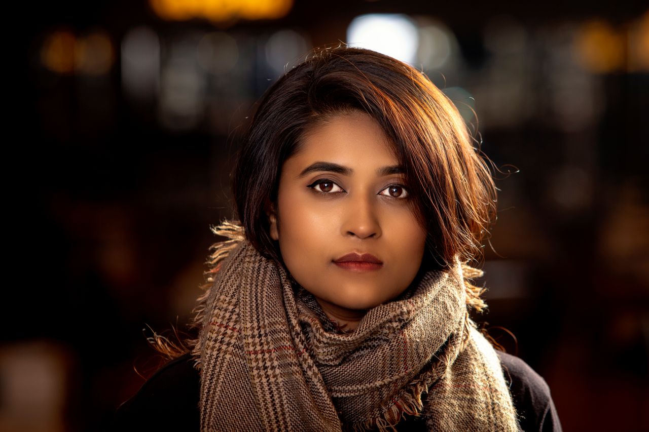 Home Elegant portrait of a woman wearing a plaid scarf, showcasing natural beauty and fashion.
